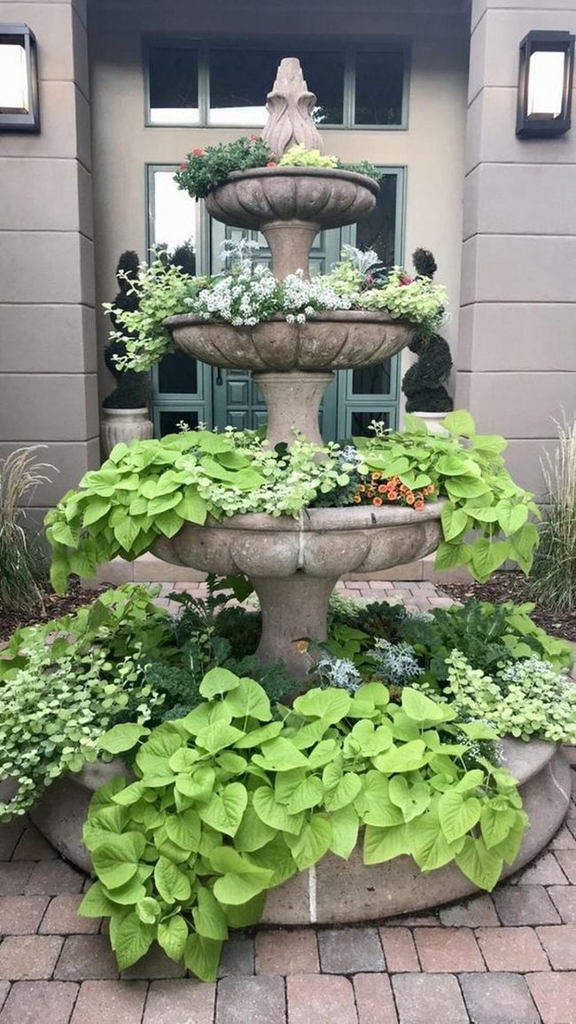 Stone Fountain Overflowing Green Foliage