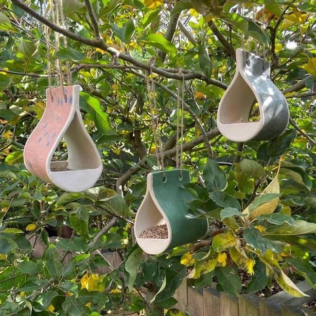 Ceramic Bird Feeders Among Green Leaves