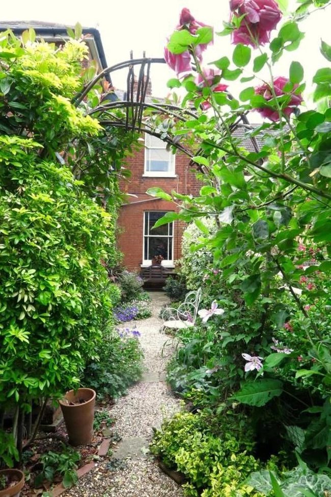 Sunlit Garden Path With Metal Archway