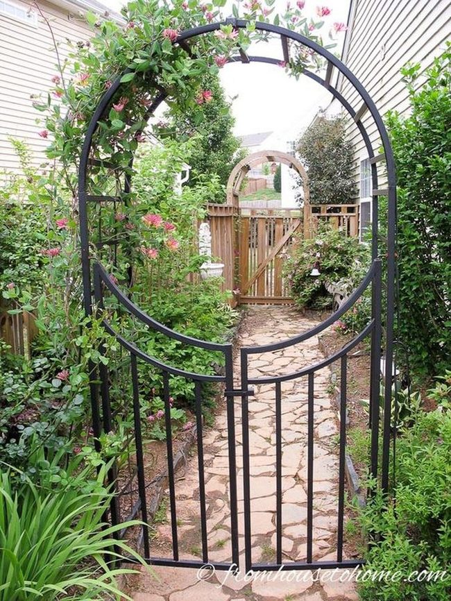 Black Metal Gates Through Pink Flowering Gardens